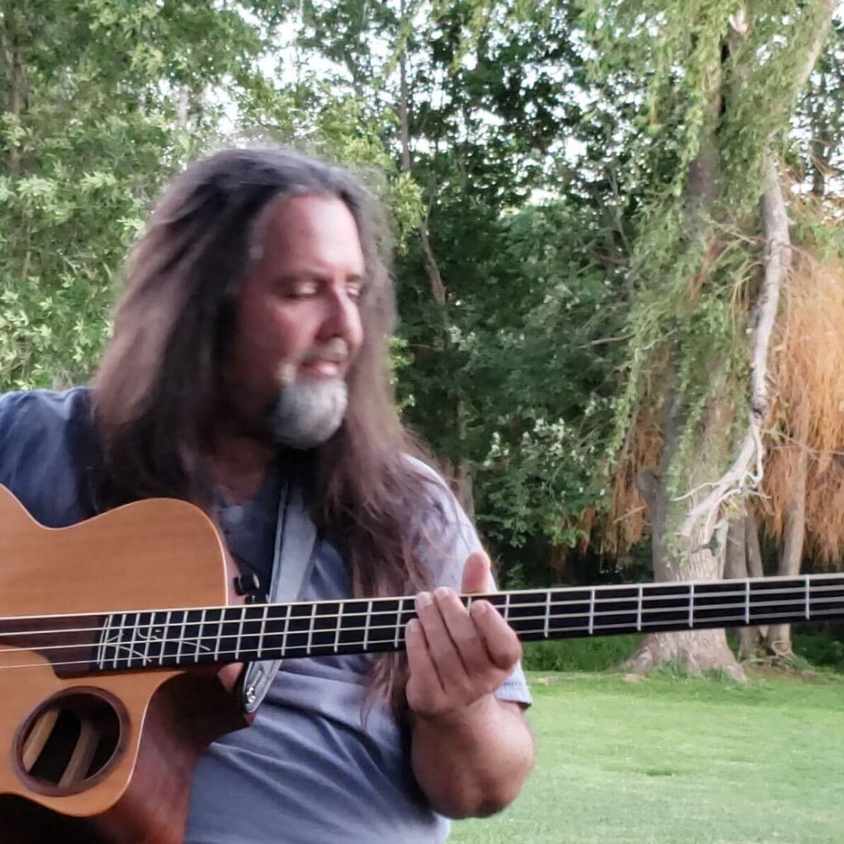 Bill Melanson playing bass guitar outdoors.